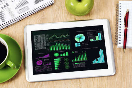 Tablet pc cup of coffee and notepad at tableの写真素材