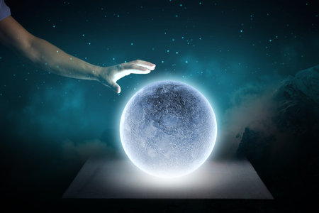 Close up of human hand touching blue glowing moon