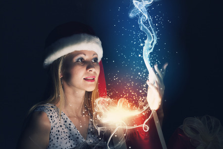 Santa woman in hat opening box with presentの写真素材
