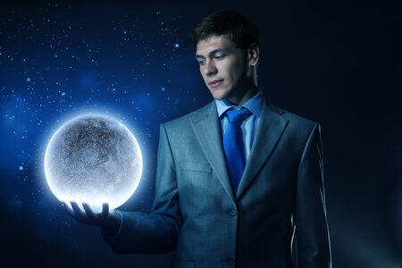 Young businessman holding moon planet in handの写真素材