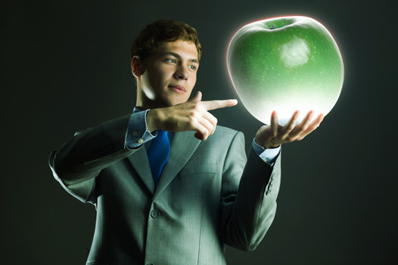 Young businessman holding green apple in handの写真素材