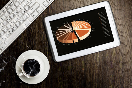Tablet pc cup of coffee and notepad at tableの写真素材