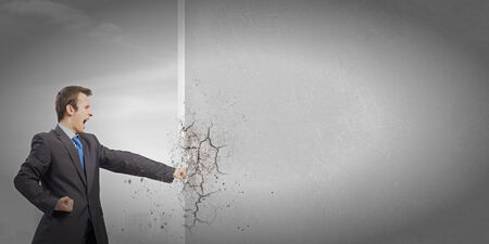 Businessman breaking stone wall with karate punchの写真素材