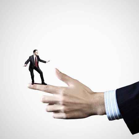 Young businessman balancing on finger of businessmanの写真素材