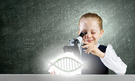 Cute school girl examining dna molecule with microscopeの写真素材