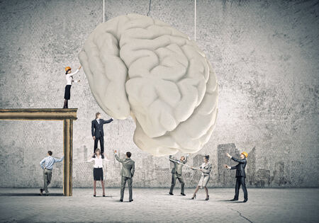 Huge human brain and many little businesspeople aroundの写真素材