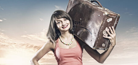 Young pretty woman tourist with suitcase walking on roadの写真素材