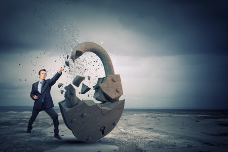 Businessman breaking stone lock with karate kickの写真素材