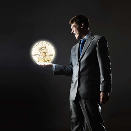 Young businessman holding cent coin in palmの写真素材