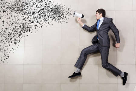 Funny image of running businessman holding megaphoneの写真素材