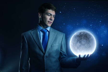 Young businessman holding moon planet in handの写真素材
