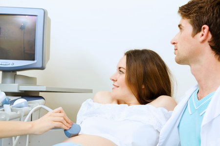 Young pregnant woman examined by doctor at ultrasound check