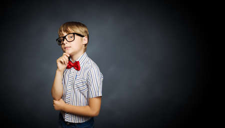 Genius boy in red glasses near blackboard with formulasの写真素材