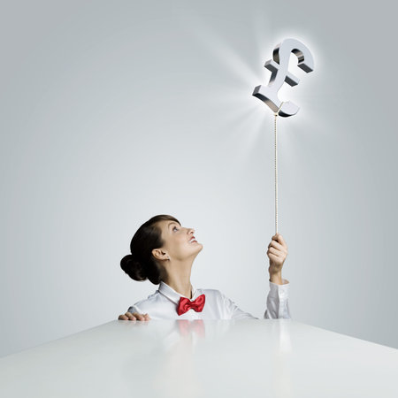 Young woman holding balloon shaped like pound signの写真素材