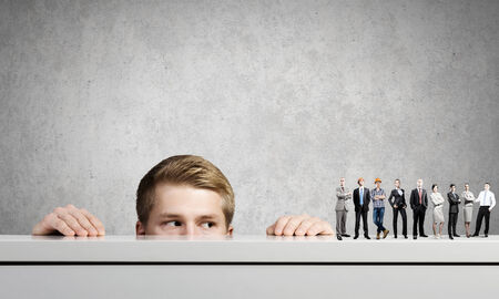 Businessman looking from under the table at businessteamの写真素材