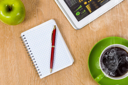 Tablet pc cup of coffee and notepad at tableの写真素材