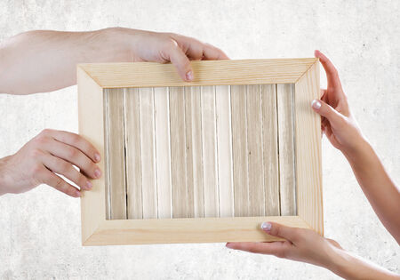 Close up of hands holding wooden blank frame  Place for textの写真素材