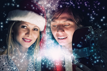 Happy family of man and woman opening Christmas giftsの写真素材