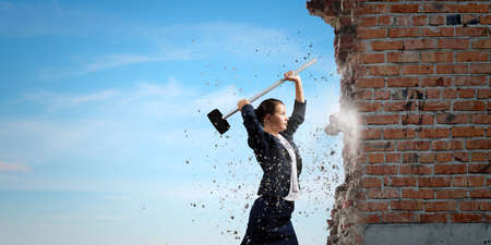 Young attractive businesswoman with hammer in handsの写真素材