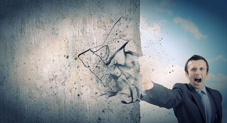 Businessman breaking stone wall with karate punchの写真素材