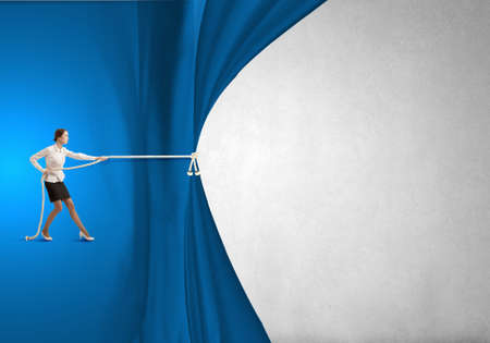 Young businesswoman pulling curtain with rope  Place for textの写真素材