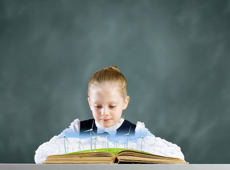 Schoolgirl looking in opened book with windmillsの写真素材