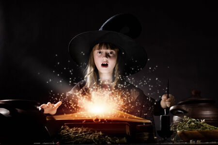 Little Halloween witch reading conjure from magic bookの写真素材