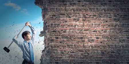 Young determined businessman with hammer in handsの写真素材