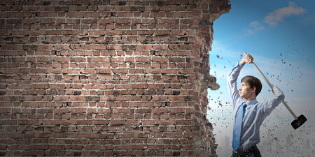 Young determined businessman with hammer in handsの写真素材