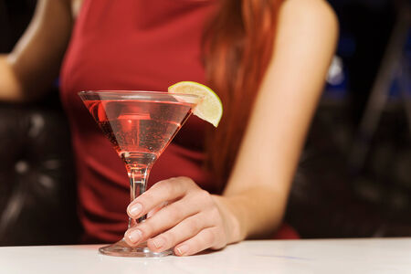 Close up of woman in red dress with cocktail in handsの写真素材
