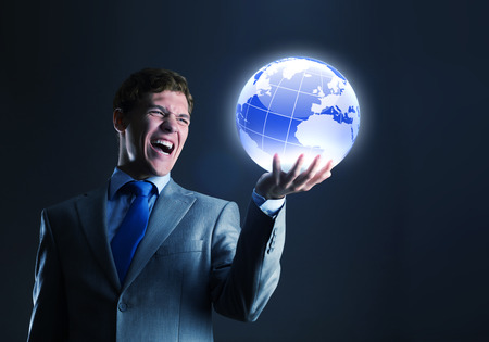 Young businessman holding digital globe in palmの写真素材