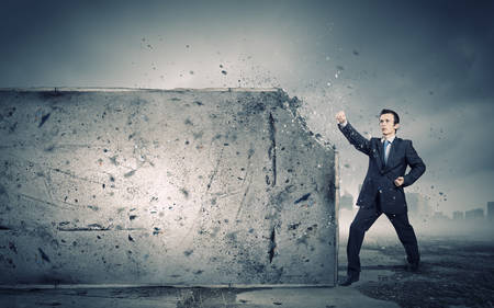Businessman breaking stone wall with karate punchの写真素材