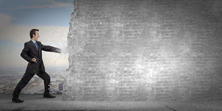 Businessman breaking stone wall with karate punchの写真素材