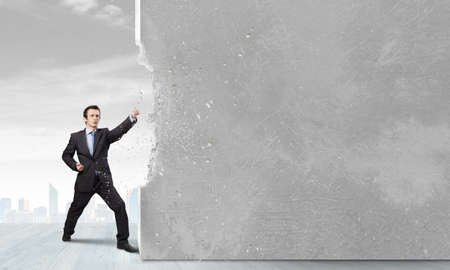 Businessman breaking stone wall with karate punchの写真素材