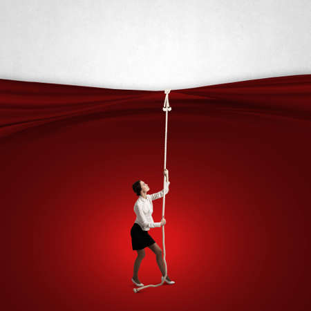 Young businesswoman pulling curtain with rope  Place for textの写真素材