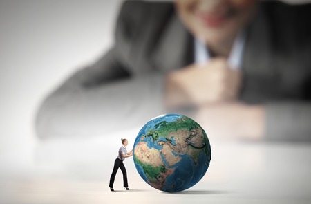 Businesswoman looking at miniature of woman rolling Earth planet  Elements of this image are furnished by NASAの写真素材