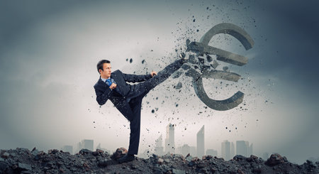 Businessman breaking stone euro symbol with karate punchの写真素材