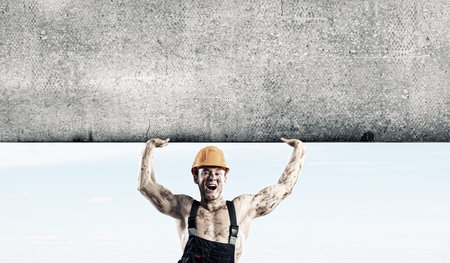 Strong man in uniform lifting wall above head