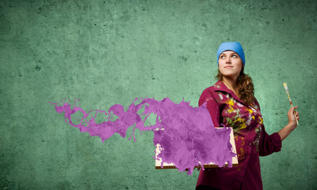Young woman painter holding frame with colorful splashes