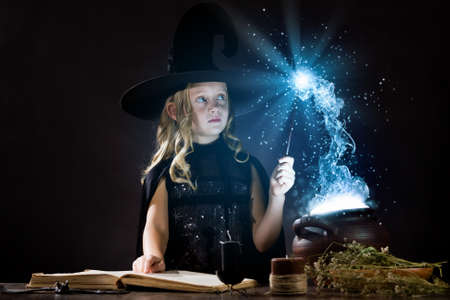 Little Halloween witch reading conjure above potの写真素材
