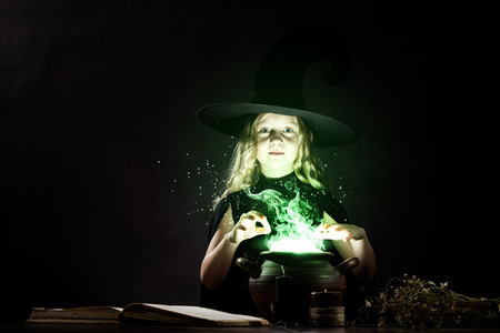 Little Halloween witch reading conjure above potの写真素材