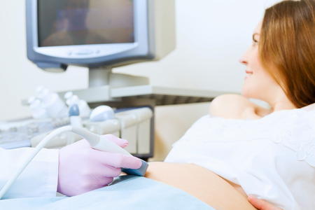 Young pregnant woman examined by doctor at ultrasound checkの写真素材