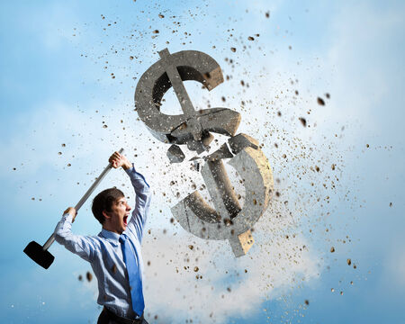 Young businessman crashing with hammer stone dollar symbolの写真素材