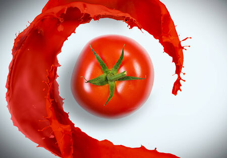 Red juicy tomato with red splashes on white backgroundの写真素材