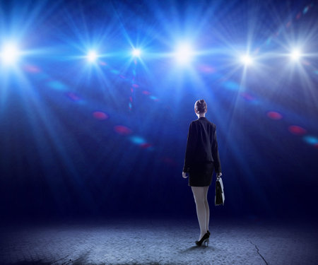Rear view of businesswoman standing in lights of stageの写真素材
