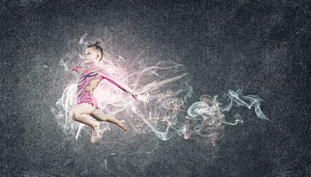 Cute girl gymnast in performance costume jumping highの写真素材