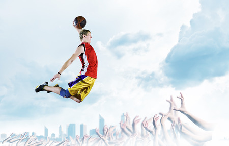 Young man basketball player with ball in hands jumping highの写真素材