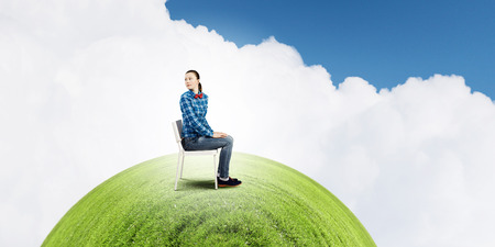 Young troubled woman sitting in chair on green planetの写真素材