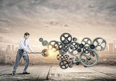 Young businessman fixing gears mechanism with wrenchの写真素材