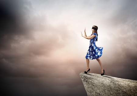 Young woman in blue dress standing on mountain edgeの写真素材